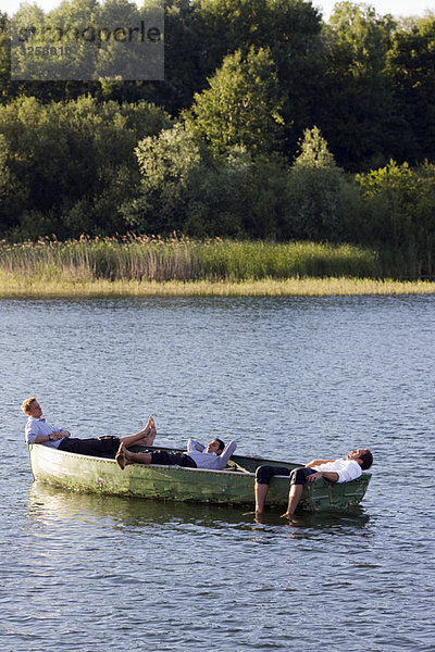 drei Geschäftsleute  die sich im Ruderboot entspannen