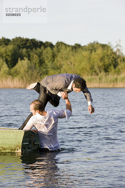 Geschäftsmann  der einen Freund ins Wasser wirft.