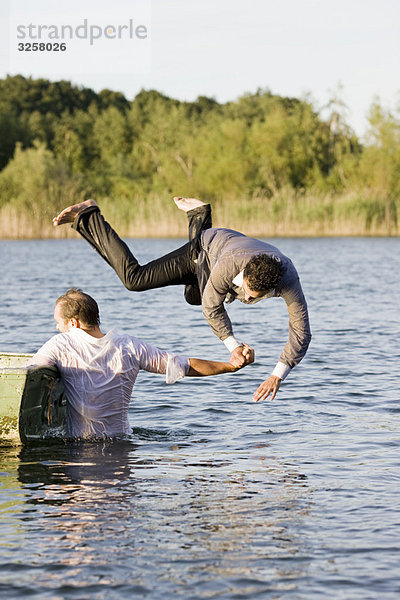 Geschäftsmann  der einen Freund ins Wasser wirft.