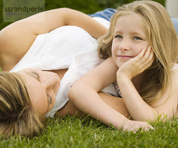 Mutter und Tochter liegen auf dem Rasen.