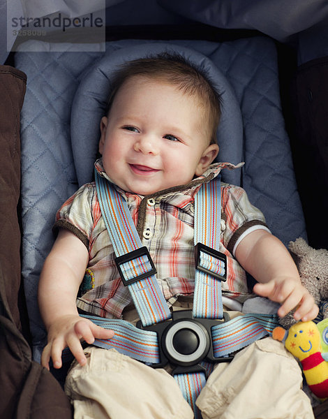 Ein kleiner Junge auf seinem Autositz lächelnd