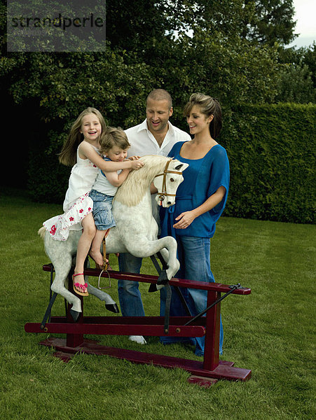 Eine Familie spielt mit einem Schaukelpferd