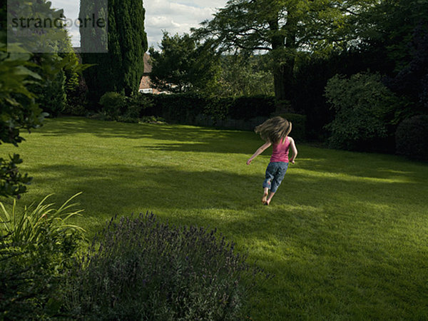 Ein junges Mädchen  das in einem Garten rennt.