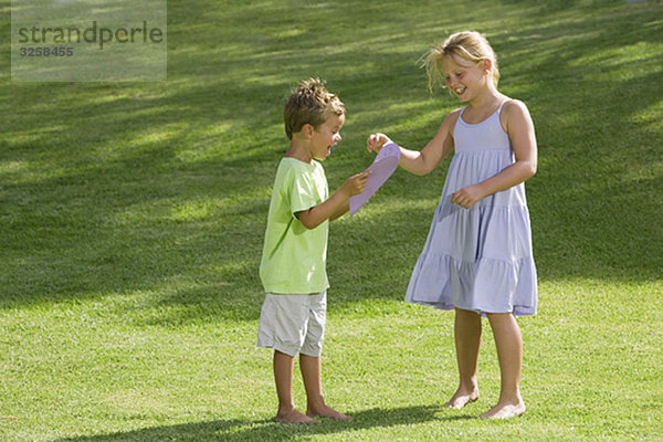 Mädchen  das dem Jungen ein Papierherz schenkt.