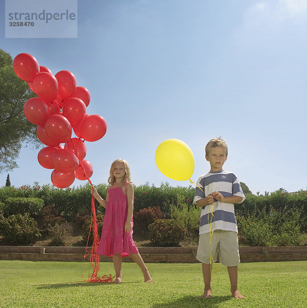 Kleine Kinder mit roten Luftballons