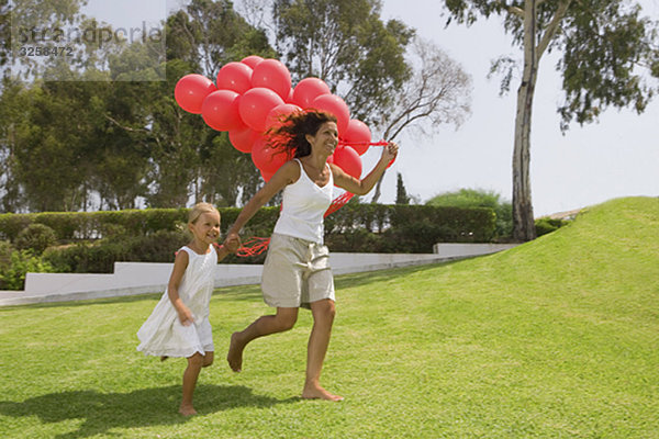 Mädchen und Mutter beim Laufen mit Luftballons