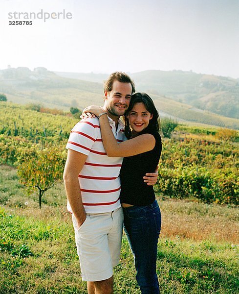 Ein lächelnd Paar in einem Weinberg in Italien.