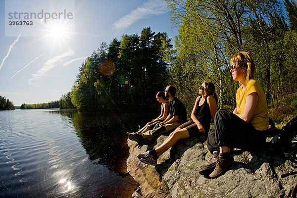 Vier Personen sitzen an einem See  Schweden.