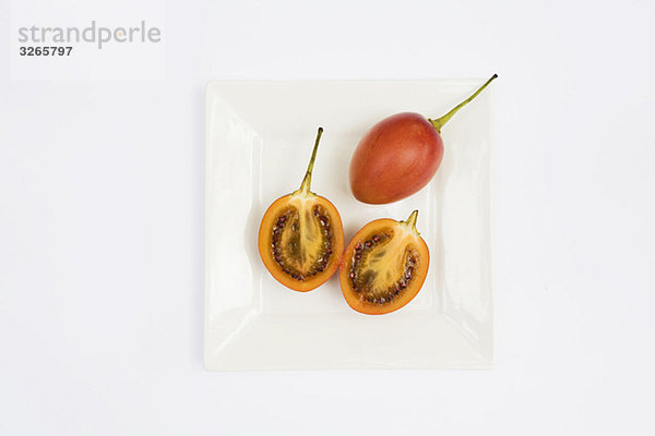 Geschnittene Tamarillos (Solanum betaceum) auf Platte  erhöhte Ansicht