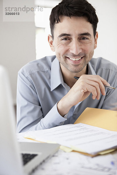 Geschäftsmann im Büro mit Kugelschreiber  lächelnd  Portrait