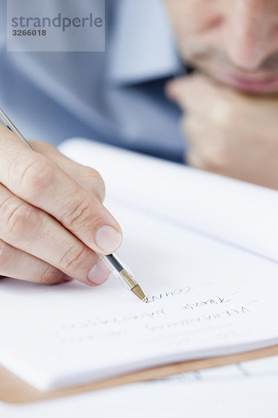 Businessman in office writing  hand in foreground