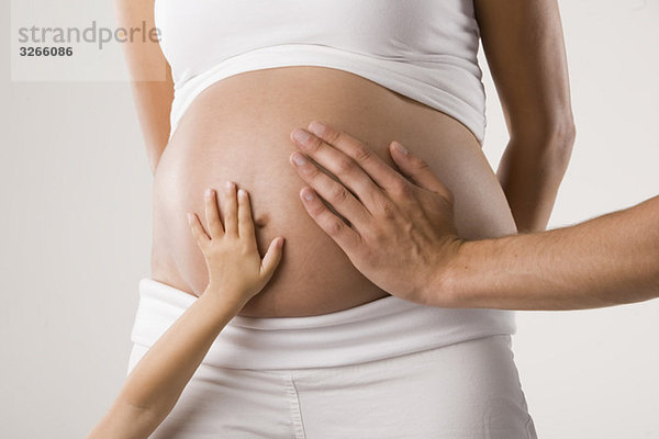 Personen  die den schwangeren Bauch der Frau berühren