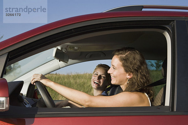 Zwei junge Frauen beim Autofahren  Seitenansicht  Portrait