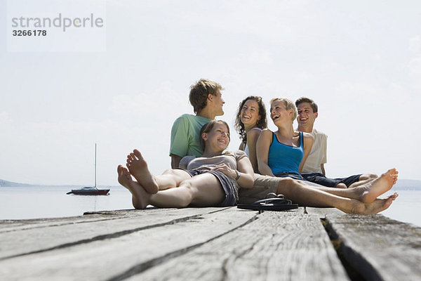 Deutschland  Bayern  Ammersee  Jugendliche sitzen am Steg  lachend  Portrait