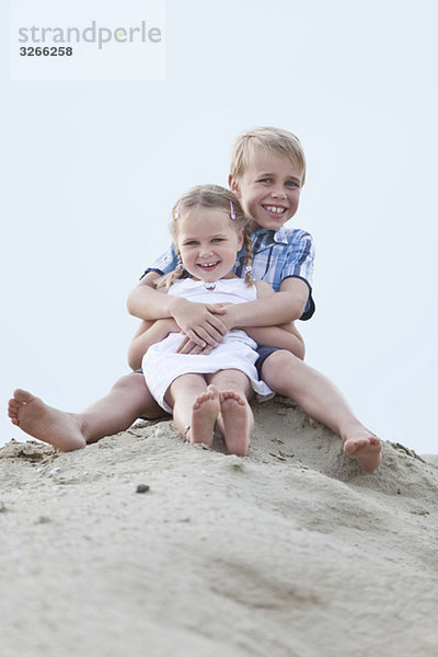 Deutschland  Kinder (4-5)  (6-7) sitzend auf Sanddüne  Portrait