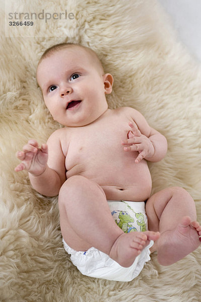 Junge (6-11 Monate) auf Fell liegend  erhöhte Ansicht