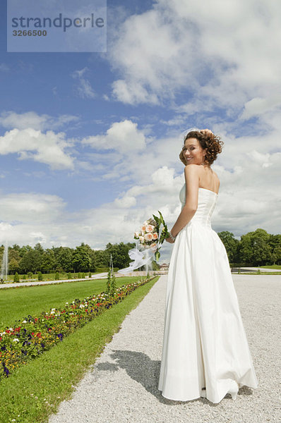 Deutschland  Bayern  Braut im Park mit Blumenstrauß  lächelnd  Portrait