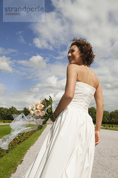 Deutschland  Bayern  Braut im Park mit Blumenstrauß  Portrait