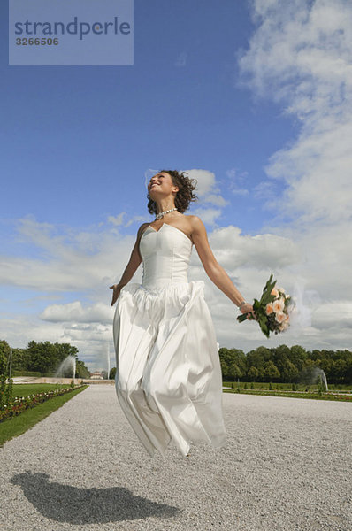 Deutschland  Bayern  Braut im Park Springen in der Luft  lächelnd  Portrait