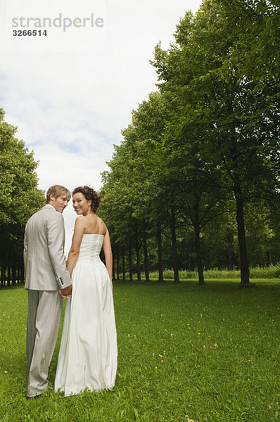 Deutschland  Bayern  Brautpaar im Park Hand in Hand  lächelnd  Portrait