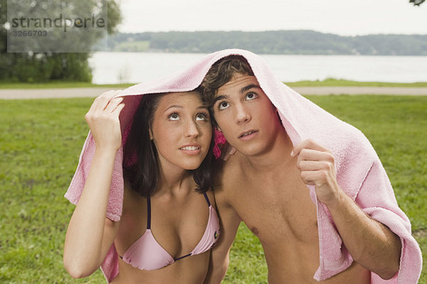 Deutschland  Bayern  Starnberger See  Junges Paar mit Handtuch über dem Kopf  Portrait  Nahaufnahme