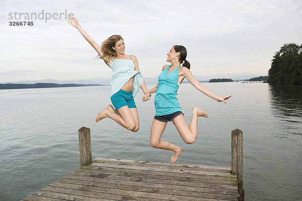 Starnberger See  Zwei junge Frauen springen auf Steg  lachend  Portrait