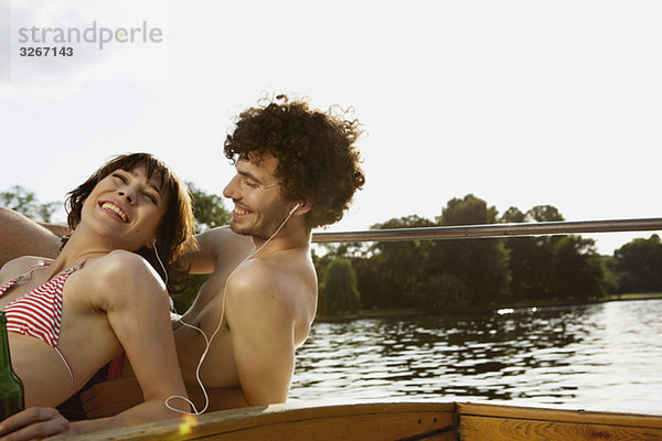 Junges Paar auf dem Motorboot  Mann mit Kopfhörer  Portrait  Nahaufnahme