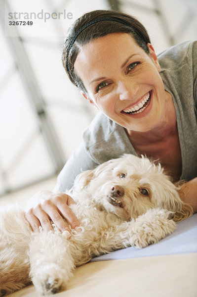 Frau auf dem Boden liegend mit Hund neben ihr  lächelnd  Portrait