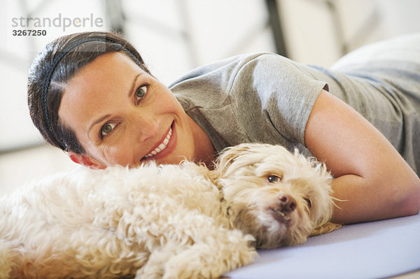 Frau auf dem Boden liegend mit Hund neben ihr  lächelnd  Portrait