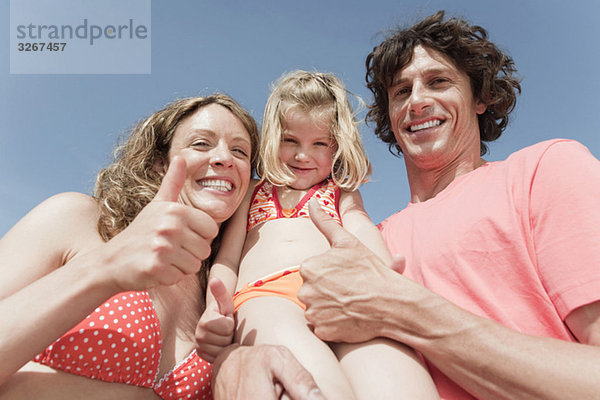 Spanien  Mallorca  Familie am Strand Daumen hoch  lachend  Portrait