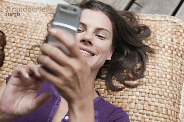 Frau auf der Terrasse liegend  mit Handy  erhöhte Aussicht