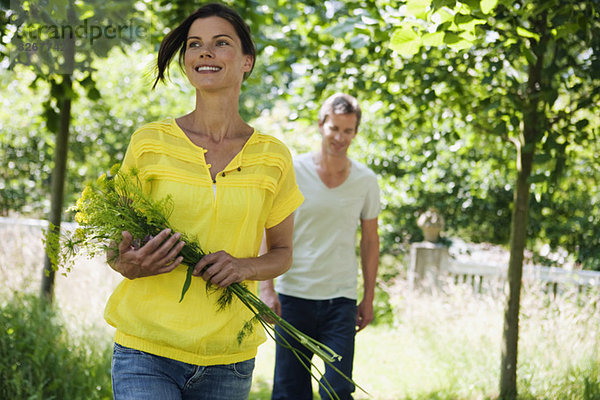 Couple in garden  woman holding bunch of flowers