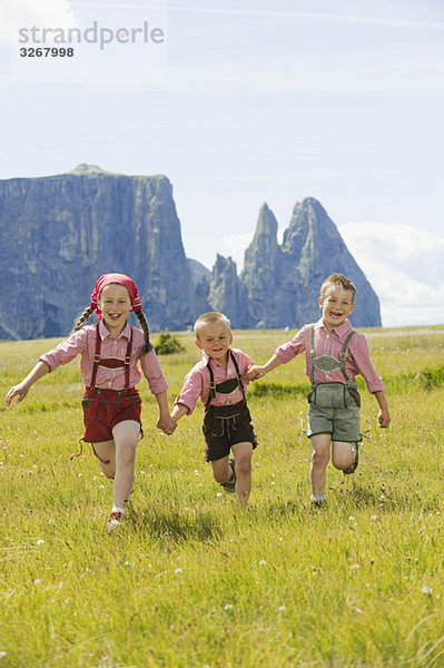 Italien  Seiseralm  Drei Kinder (4-5)  (6-7)  (8-9) beim Laufen im Feld