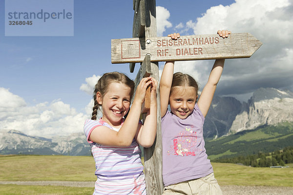 Italien  Seiseralm  Mädchen (6-9) mit Wegweiser  lächelnd  Portrait