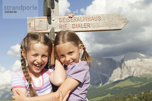 Italien  Seiseralm  Mädchen (6-9) am Wegweiser  lächelnd  Portrait  Nahaufnahme