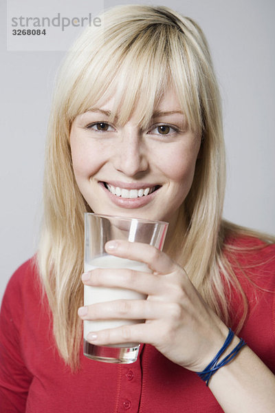 Junge Frau mit Milchglas  lächelnd  Nahaufnahme