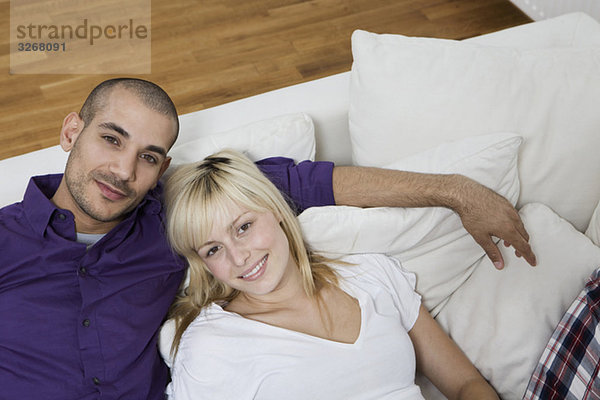 Deutschland  Berlin  Junges Paar auf Sofa sitzend  lächelnd  Portrait