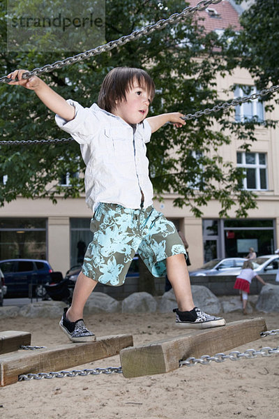 Junge (3-4) auf Spielplatz auf Hängebrücke