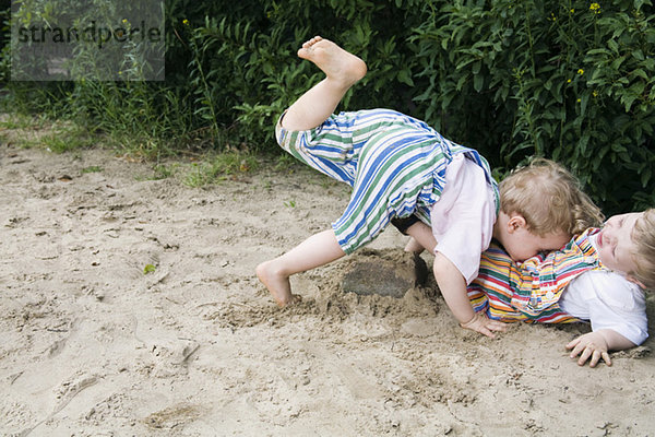 Zwei Jungen (1-3)  die zusammen im Sand spielen