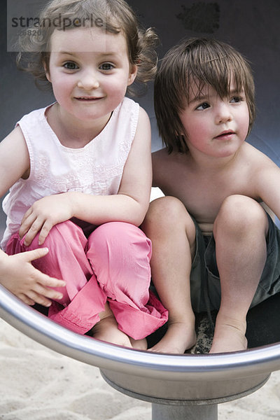 Junge und Mädchen (3-4) auf dem Spielplatz  Seite an Seite  Portrait