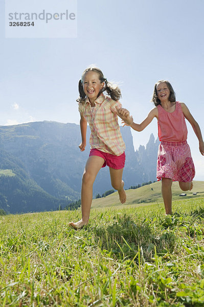 Italien  Südtirol  Seiseralm  Zwei Mädchen (6-7) (10-11) beim Laufen im Feld