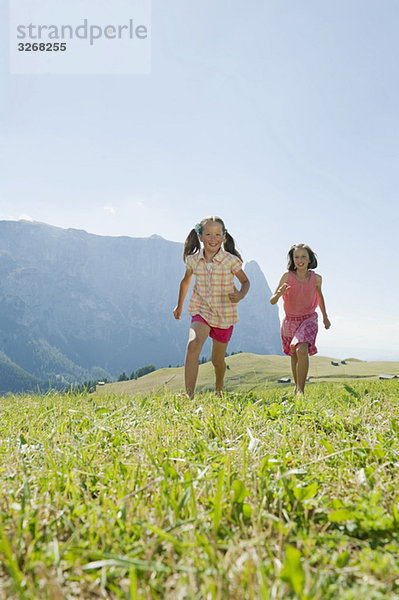 Italien  Südtirol  Seiseralm  Zwei Mädchen (6-7) (10-11) beim Laufen im Feld