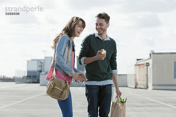 Junges Paar auf Parkebene stehend lachend  Mann mit Apfel  Porträt