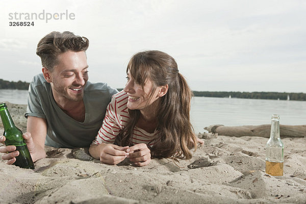 Deutschland  Berlin  Wannsee  Junges Paar am Strand liegend  lächelnd  Portrait