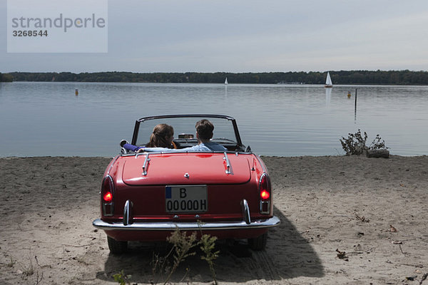 Deutschland  Berlin  Wannsee  Junges Paar im Cabriolet mit Blick auf den See  Rückansicht
