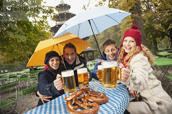 Deutschland  Bayern  Englischer Garten  Vier Personen sitzend im verregneten Biergarten