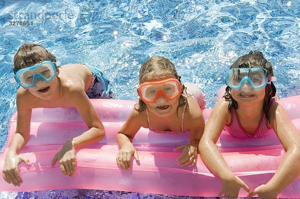 Drei Kinder auf einer Hüpfburg im Pool