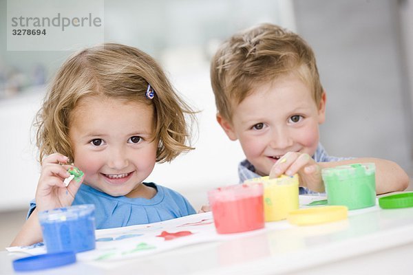 junges Mädchen und Junge spielen mit Farben