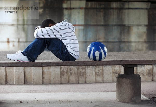 Junge sitzend mit Ball