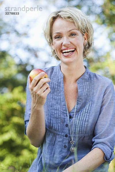 Frau lächelnd haltend Apfel